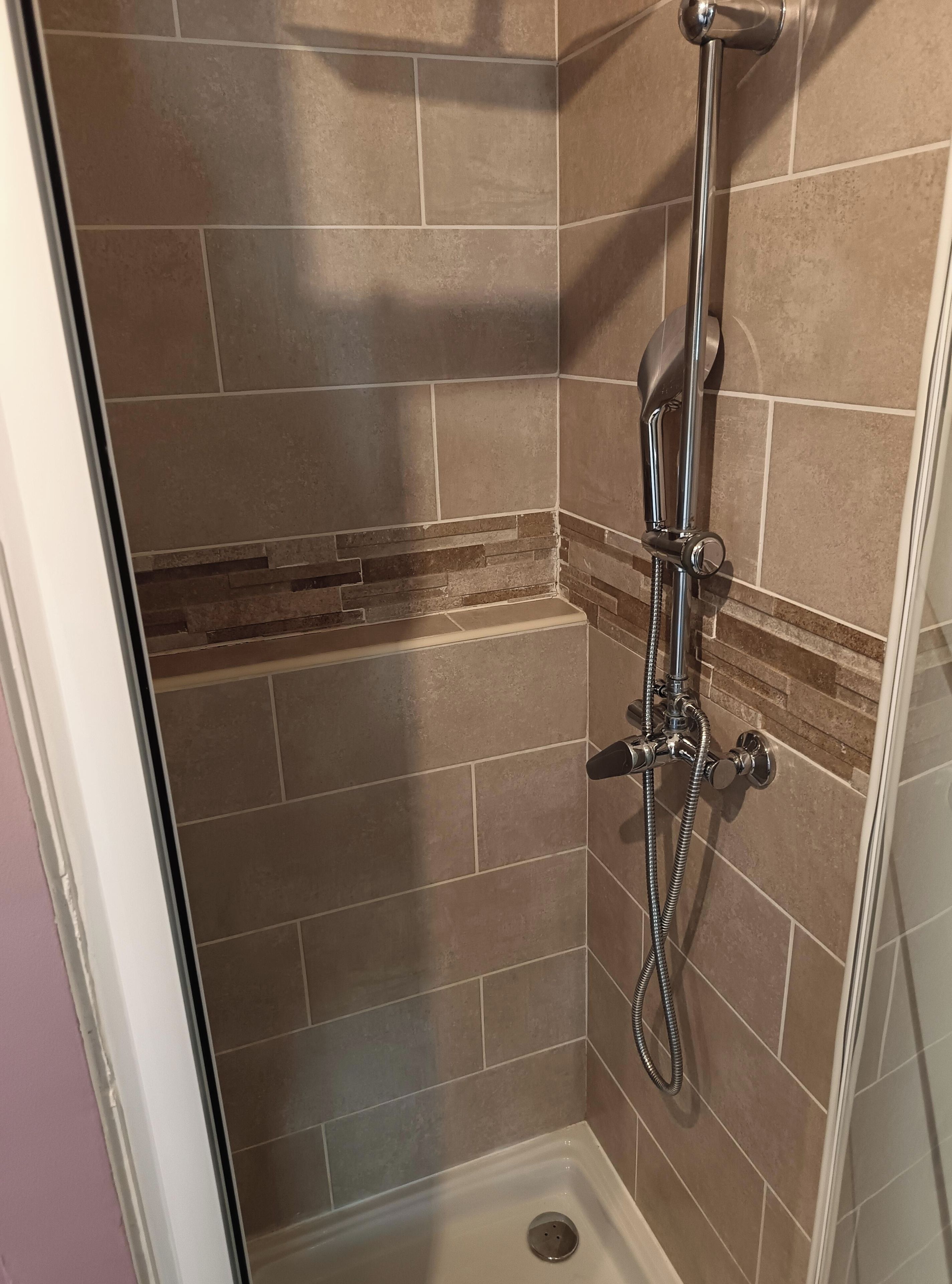Een douche met een handdouche en een muurbevestigde kraan.