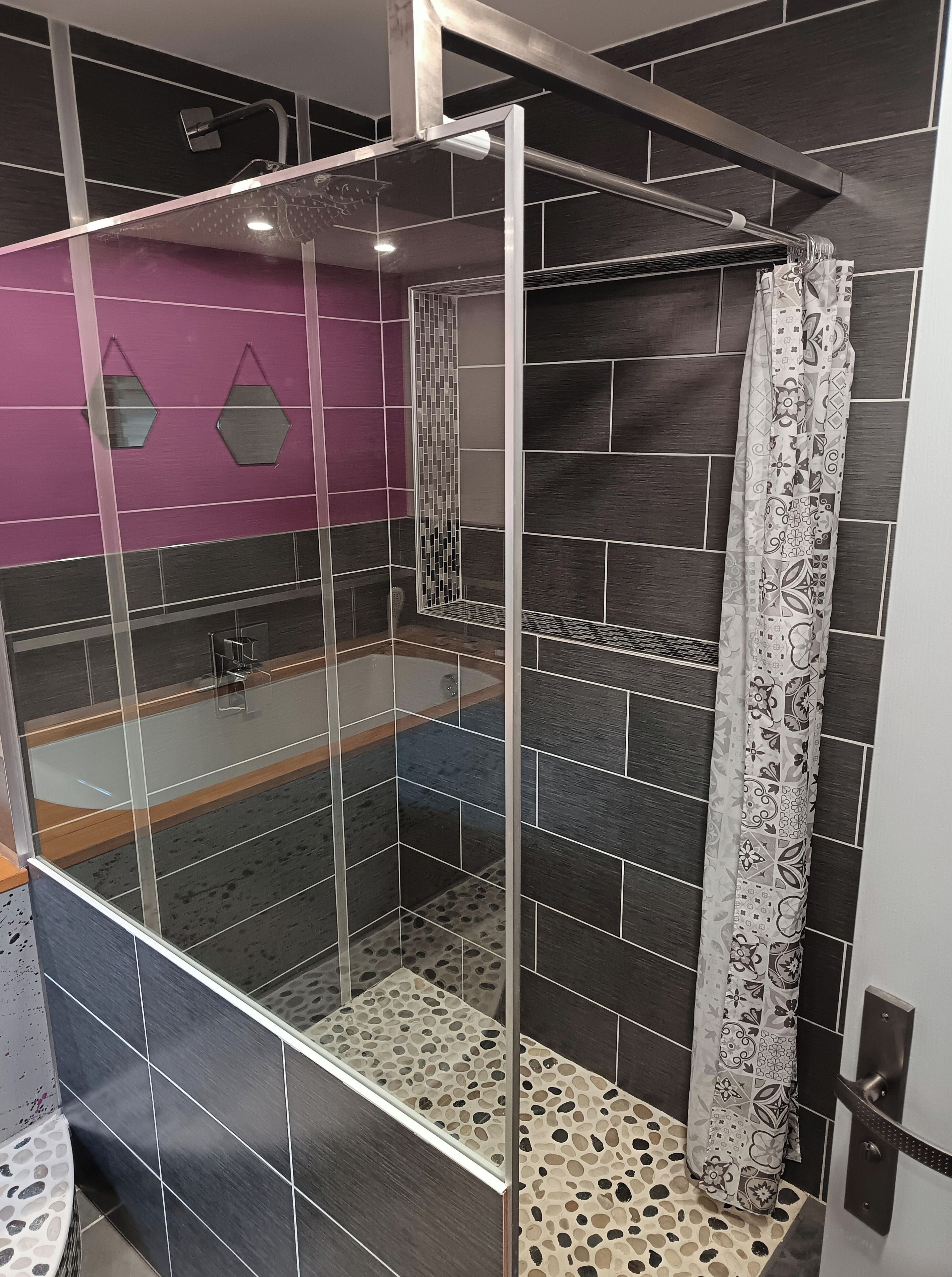 Une salle de bain moderne avec une douche à parois de verre, une baignoire et un rideau de douche à motifs.