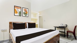 Ett hotellrum med en säng, ett skrivbord, en stol och två konstverk som hänger på väggen.