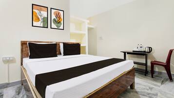 Habitación de hotel con cama, escritorio, silla y dos obras de arte colgadas en la pared.