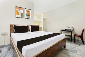 A hotel room with a bed, a desk, a chair, and two wall-mounted artworks. - Super Hotel O Khandagiri (Bhubaneswar)