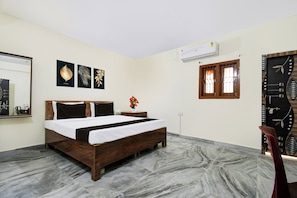 A hotel room with a bed, a nightstand, a mirror, and a wall-mounted air conditioner. - Super Hotel O Khandagiri (Bhubaneswar)