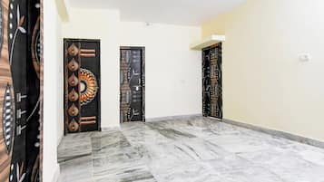 A hallway with three doors, each with a unique design, leading to rooms. The floor is tiled with a marble pattern.