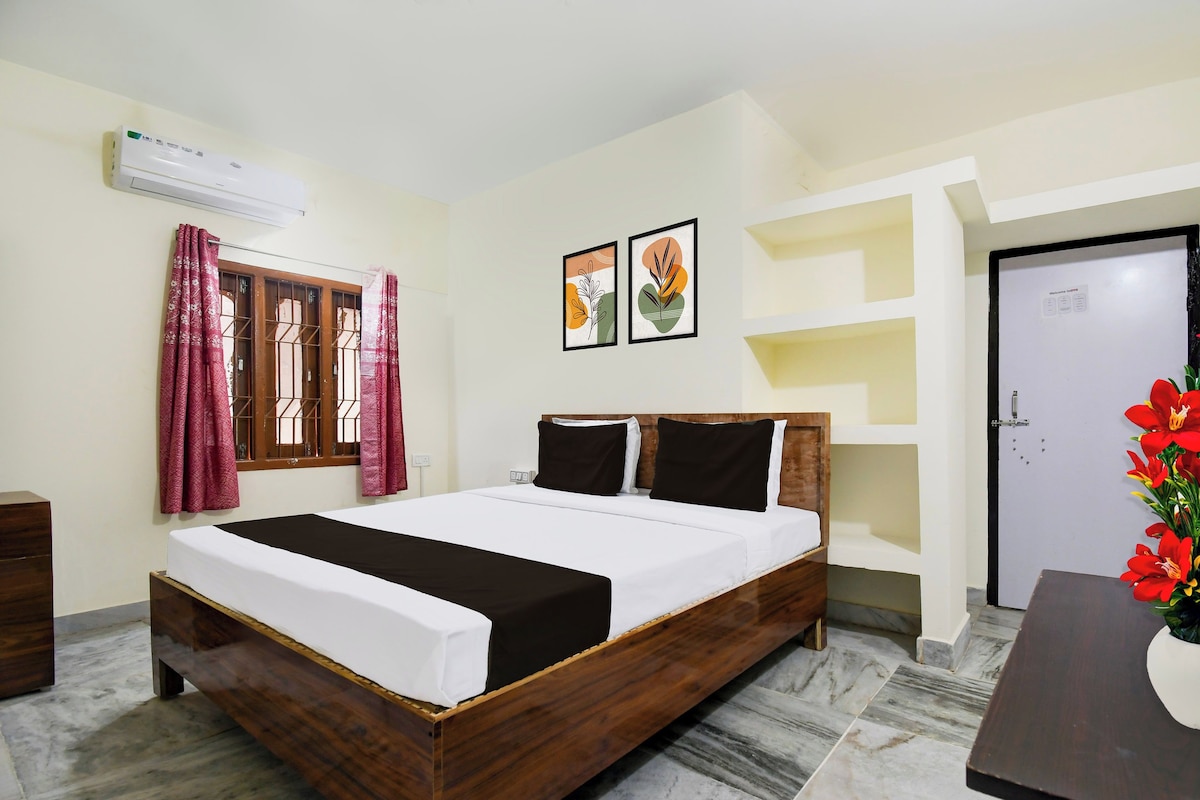 A hotel room with a wooden bed, a window with curtains, a wall-mounted air conditioner, and a door.