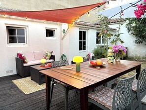 An outdoor patio with a wooden table, chairs, a sofa, and a decorative lamp. - One-time rental: “Fouras on Foot” (Fouras)