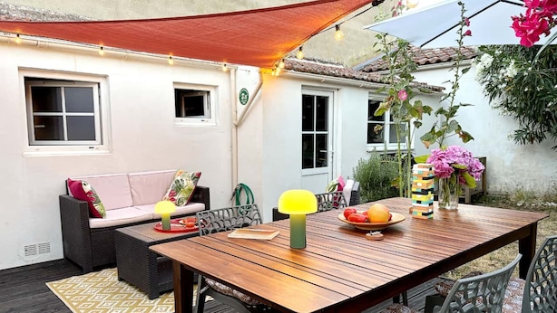 Eine Terrasse im Freien mit einem Holztisch, Stühlen, einer Couch und einer Tischlampe.