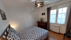 Ein Schlafzimmer mit einem Bett, einem Heizkörper, einem Fenster mit Vorhängen und einem Holzboden.