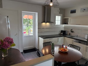 A modern kitchen with a dining area, featuring a built-in stove, a large window, and a dining table with chairs. - One-time rental: “Fouras on Foot” (Fouras)