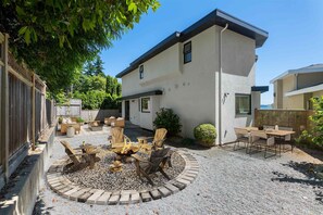 Ein modernes Haus mit Terrasse, Gartenmöbeln und einem Feuerkorb.