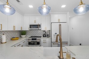 A modern kitchen with white cabinets, a stainless steel refrigerator, a gas stove, and a built-in oven. - Block from the Beach – Pristine Avalon Condo Just One Block from the Beach! (Avalon)