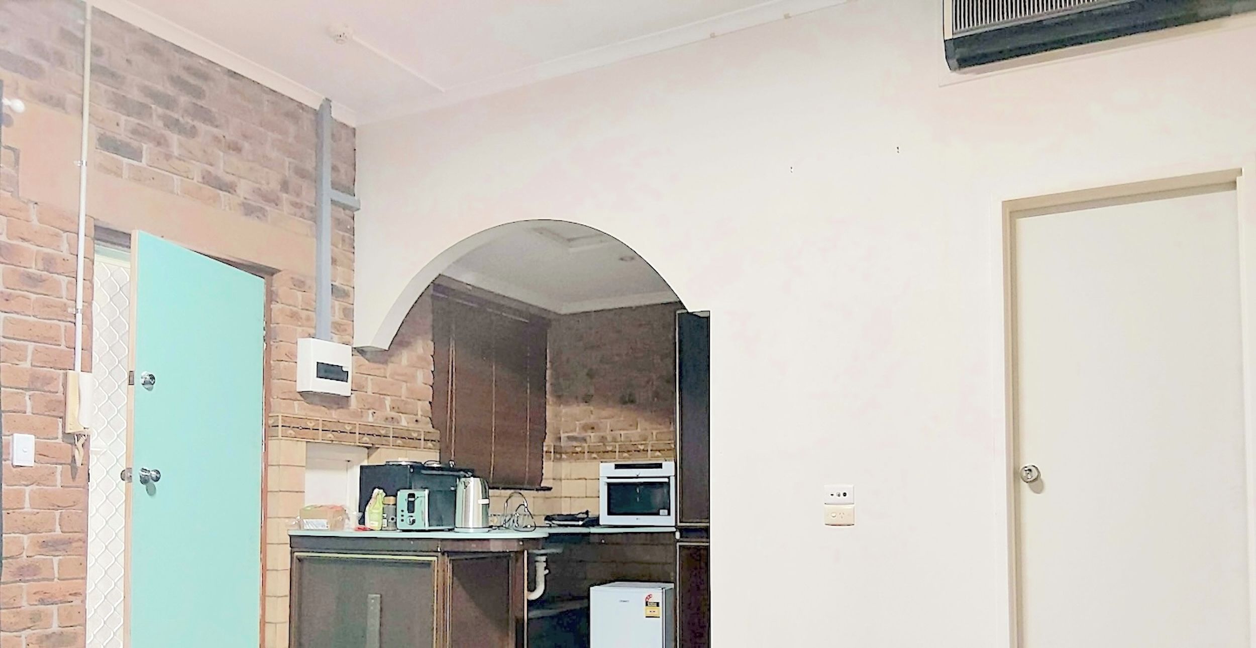 A compact kitchen with a microwave, kettle, and a small refrigerator.