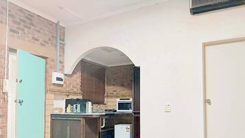 A compact kitchen with a microwave, kettle, and a small refrigerator.