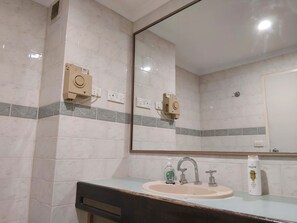 A bathroom with a sink, mirror, and two wall-mounted devices.