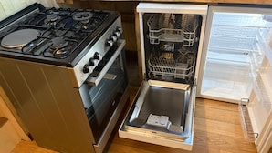 Une cuisine compacte dotée d’une cuisinière, d’un four et d’un lave-vaisselle intégrés.