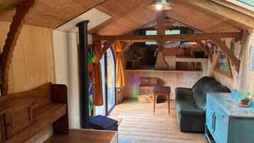 Een gezellig houten interieur met een bankje, een slaapbank, een tafel en een rustiek plafond.
