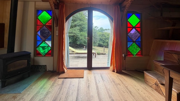 Un intérieur en bois avec une grande porte vitrée donnant sur l’extérieur, une cheminée et un banc.
