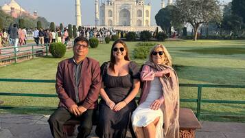 A group of people sitting on a bench with the Taj Mahal in the background.