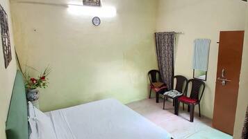 A bedroom with a bed, a ceiling fan, a clock, and a door.