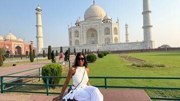 A person sitting on a bench with the Taj Mahal in the background.
