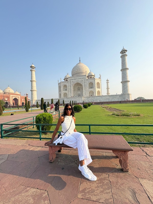 Una persona sentada en un banco con el Taj Mahal al fondo.