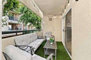 A balcony with a sofa, chairs, a table, and string lights. - Stylish 3BR Woodland Hills with Private Balcony (Los Angeles)