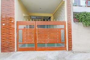 A double metal gate with vertical bars and decorative elements, leading to a building entrance. - Super Hotel O Sudhirpur (Varanasi)