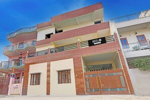 A multi-story hotel with balconies, a sign indicating it's a company service hotel, and a gated entrance. - Super Hotel O Sudhirpur (Varanasi)