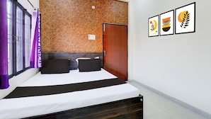 Une chambre d’hôtel avec un lit, une tête de lit en bois, une porte et trois œuvres d’art encadrées accrochées au mur.