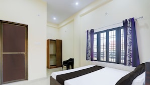 Une chambre à coucher avec un lit, une armoire, une chaise et une fenêtre avec des rideaux.