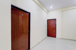 A hallway with two wooden doors, numbered 103 and 102, and a light switch on the wall. - Super Hotel O Sudhirpur (Varanasi)