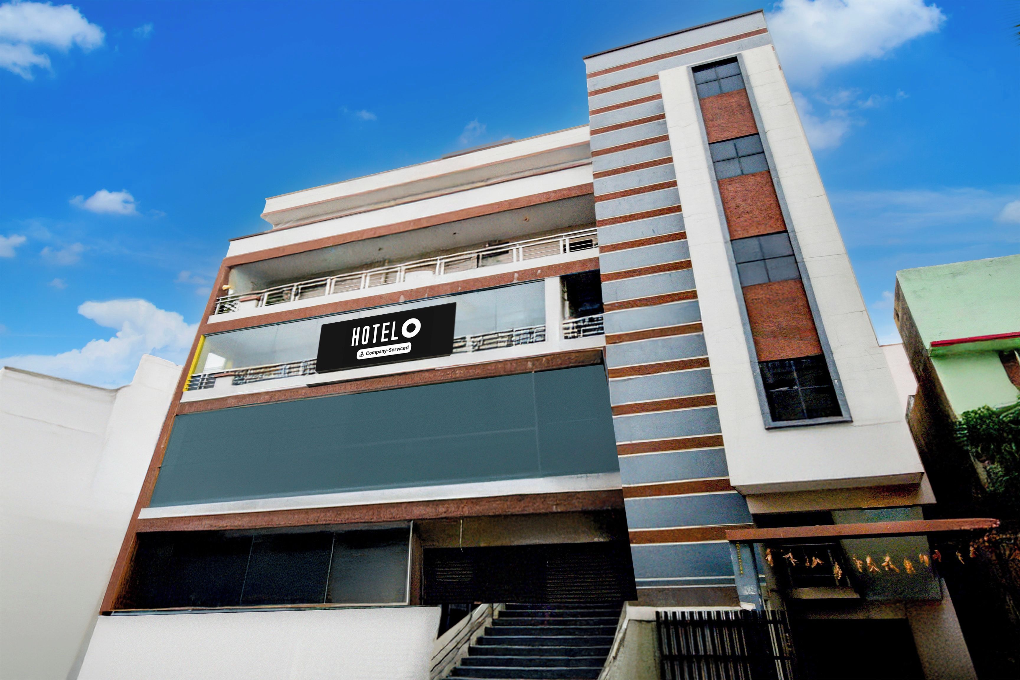 Un hotel moderno con un cartel llamativo, varios pisos y una escalera que conduce a la entrada.
