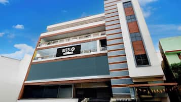 Un hotel moderno con un cartel llamativo, varios pisos y una escalera que conduce a la entrada.