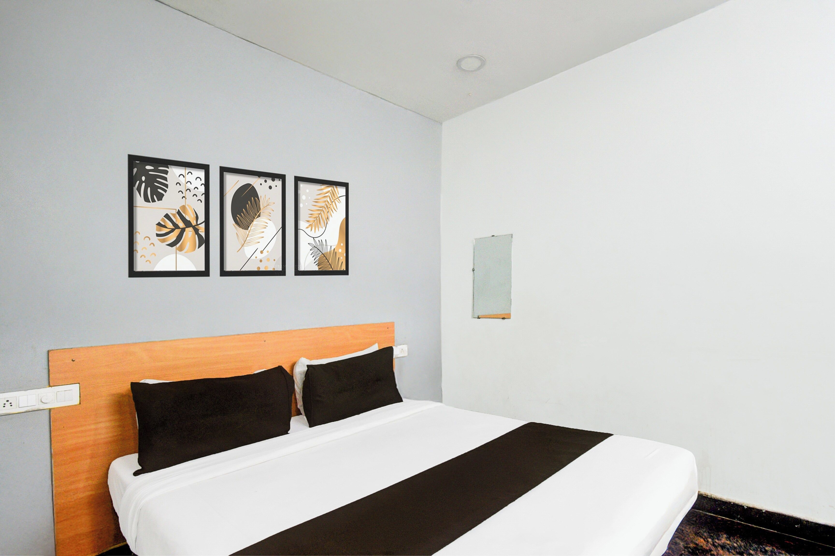 Een hotelkamer met een bed, een houten hoofdeinde en drie ingelijste kunstwerken aan de muur.