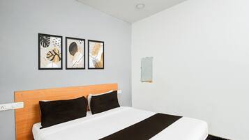 Een hotelkamer met een bed, een houten hoofdeinde en drie ingelijste kunstwerken aan de muur.