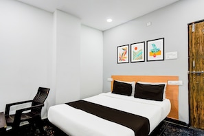 Una habitación de hotel con una cama, una silla y tres cuadros en la pared.