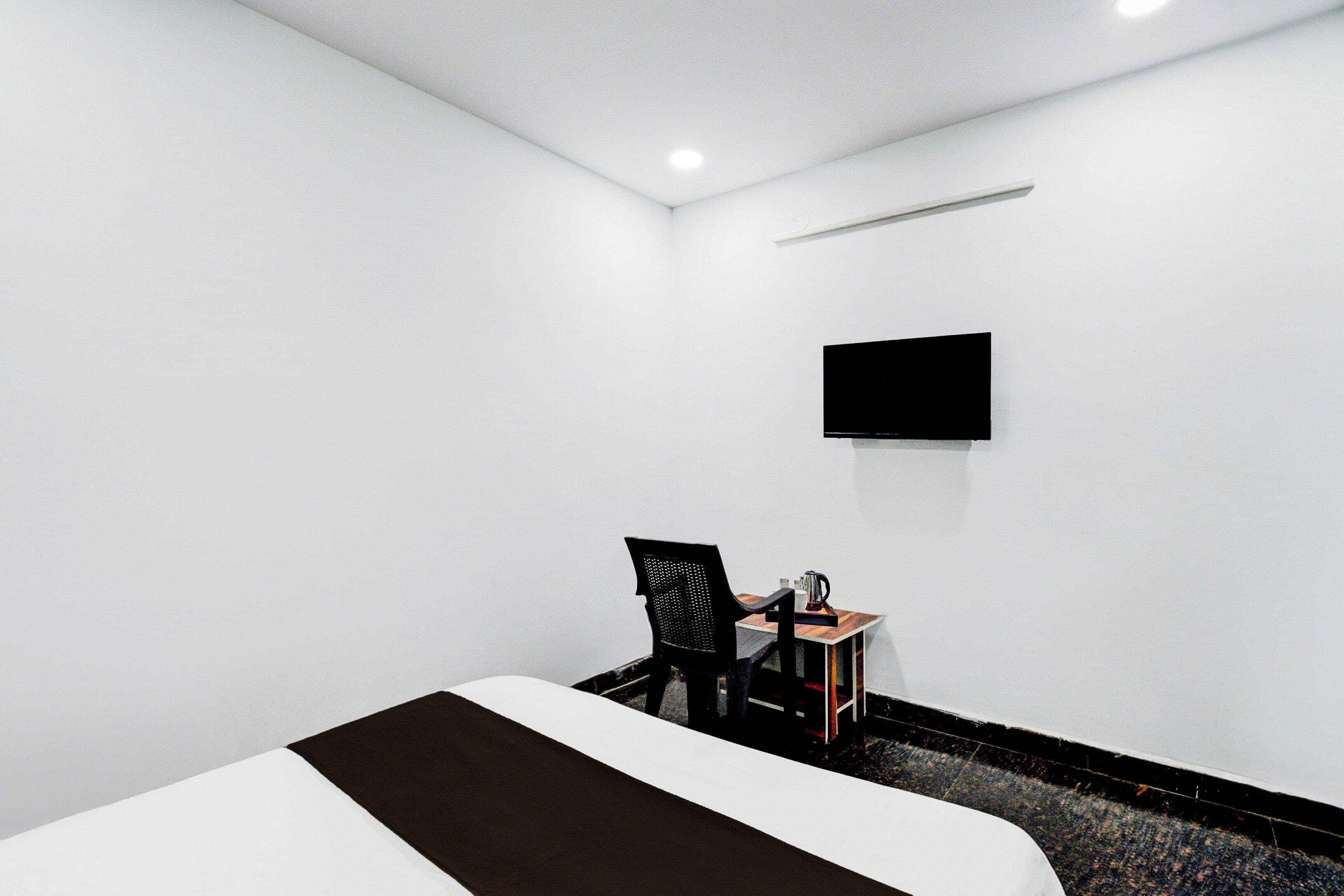 Habitación de hotel con cama, escritorio con silla, televisor de pantalla plana en la pared y piso alfombrado.