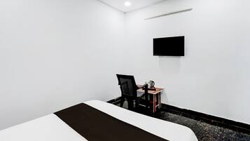Habitación de hotel con cama, escritorio con silla, televisor de pantalla plana en la pared y piso alfombrado.