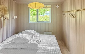 A bedroom with a bed, a window, and a hanging light fixture. - Nice home in Rønne with WiFi (Rønne)