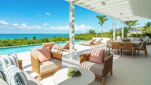 A covered outdoor area with lounge chairs, a pool, and a view of the ocean. - FORGET-ME-NOT (Blue Mountain Road)