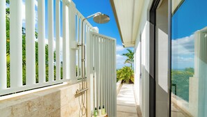 A modern bathroom with a shower, a small wooden stool, and a glass door leading to a balcony with a view. - FORGET-ME-NOT (Blue Mountain Road)