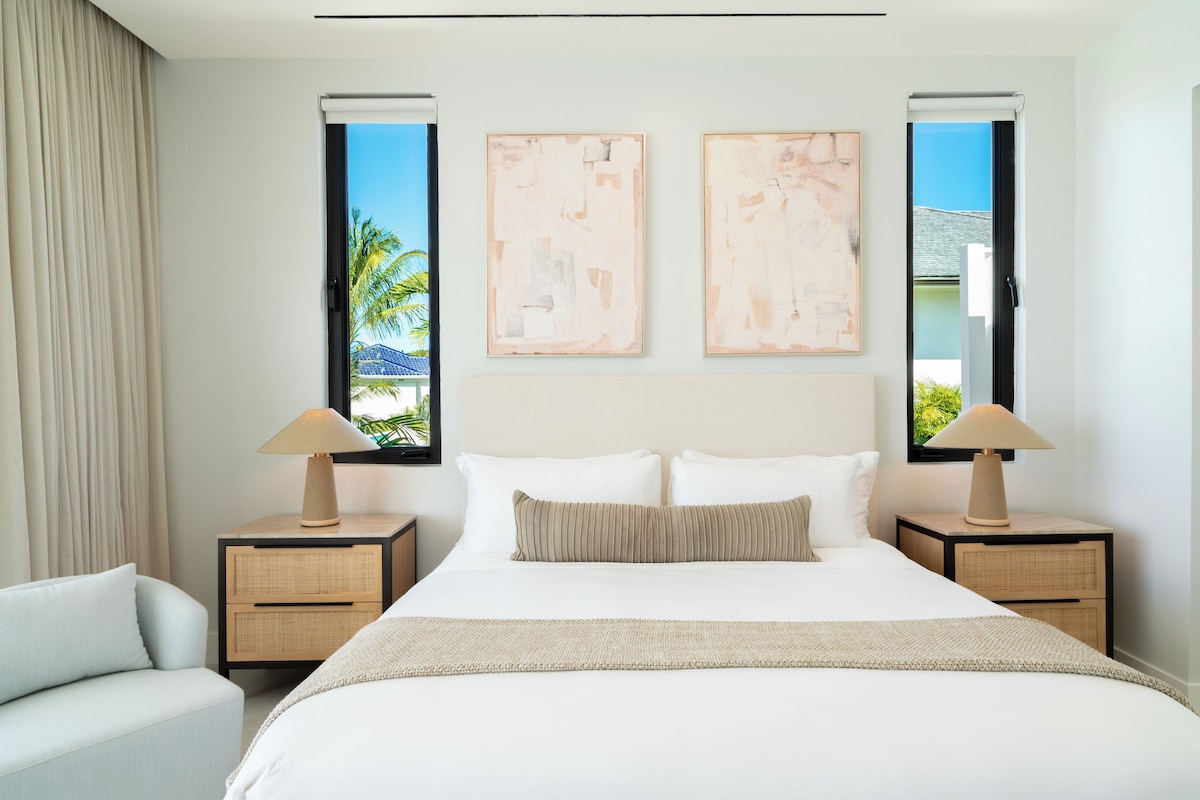A hotel room with a large bed, two nightstands, a chair, and artwork on the walls.
