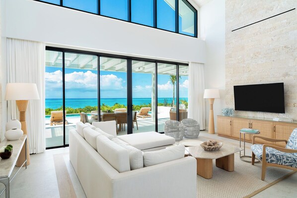 A modern living room with a large sofa, a coffee table, and a TV mounted on a brick wall.