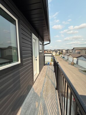 A residential building with a balcony, a garage, and a clear view of neighboring houses. - Cozy Laneway Suite in Harbour Landing (Regina)