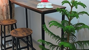 A small room with a wooden table, two stools, and a potted plant. - Apartment Valley of legends mall  (Namangan)