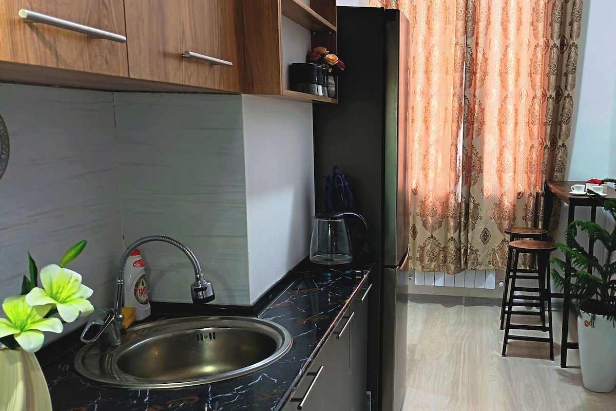 Cozinha moderna com pia, cafeteira e armário.