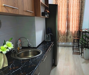 Cozinha moderna com pia, cafeteira e armário.