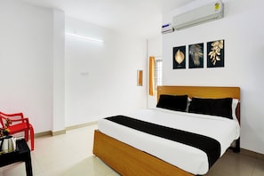 A hotel room with a bed, a red chair, a small table with a kettle, and a wall-mounted air conditioner. - Collection O Ambattur Near Patravakam (Chennai)
