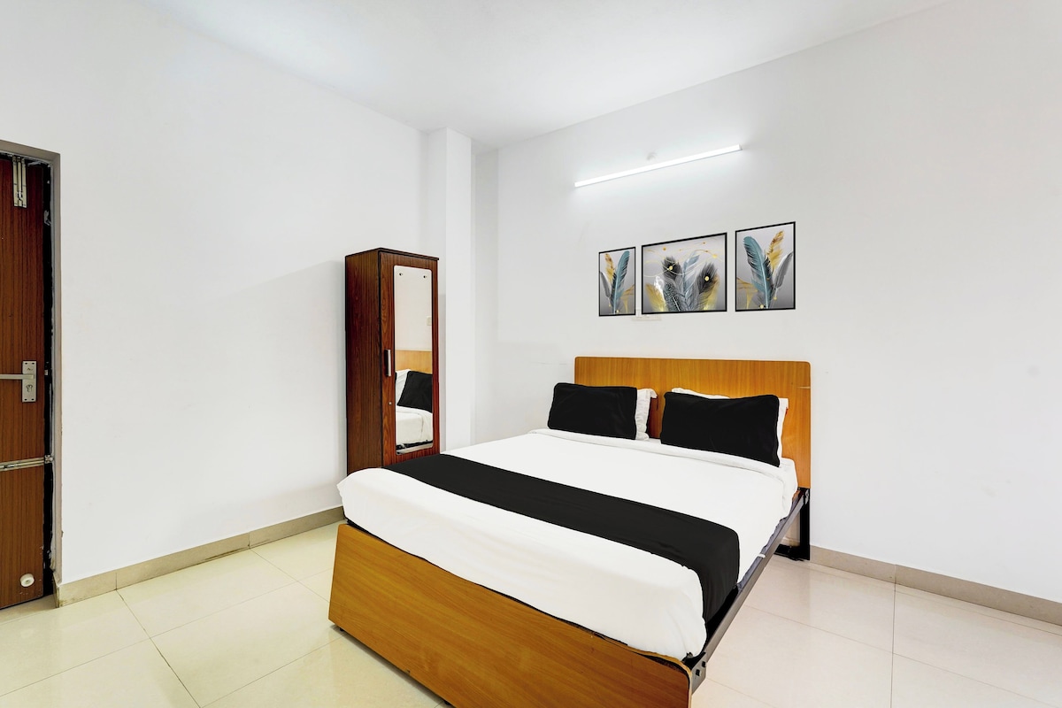 A bedroom with a wooden bed, a mirror, and three framed artworks on the wall.