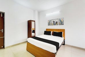 A bedroom with a wooden bed, a mirror, and three framed artworks on the wall. - Collection O Ambattur Near Patravakam (Chennai)