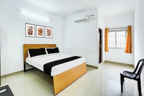 A hotel room with a bed, a chair, an air conditioning unit, a window with curtains, and framed artwork on the wall. - Collection O Ambattur Near Patravakam (Chennai)